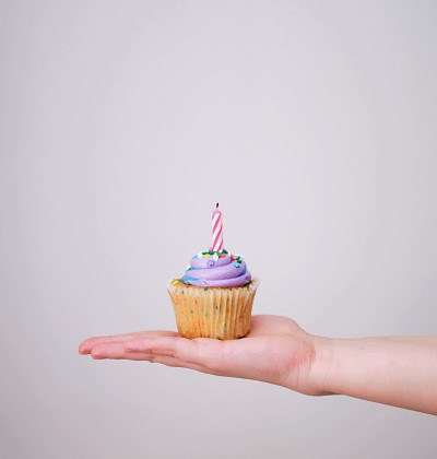 Birthday cupcake with a candle in the palm of a hand